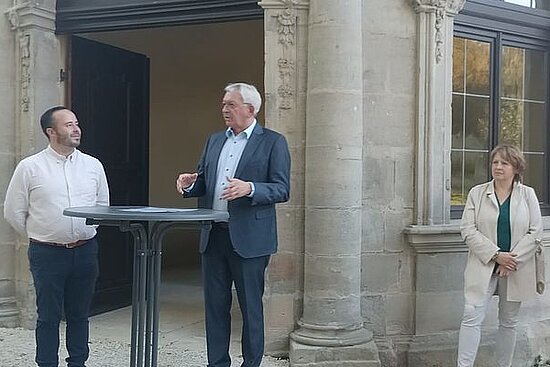 Personen an einem runden Stehtisch vor Kloster Ebrach