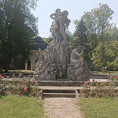 Brunnen mit Statuen umringt von Blumen
