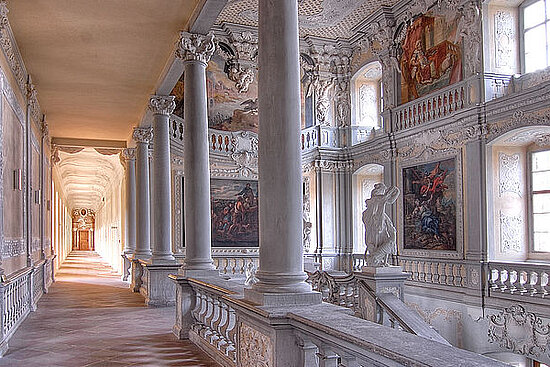 Treppenhaus mit Säulen und Gemälden