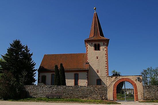 Kirche mit Mauer und Torbogen im Vordergrund